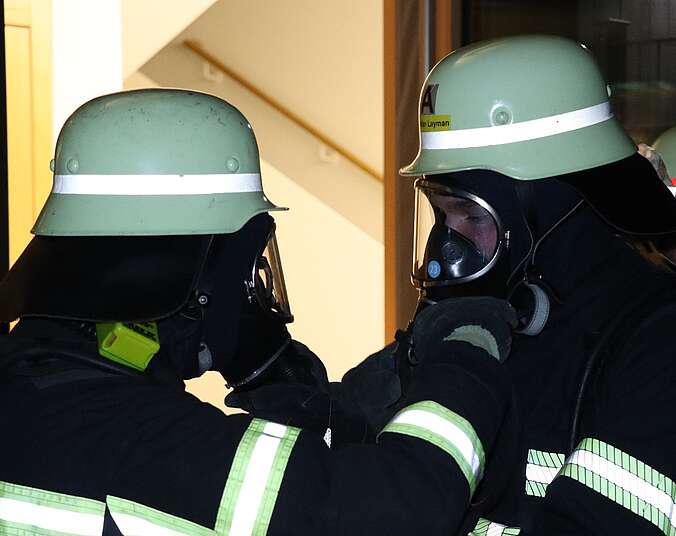 Zwei Feuerwehrmänner mit Helm und Atemschutz