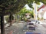 Biergarten mir schönen alten Bäumen und Sonnenschirmen.