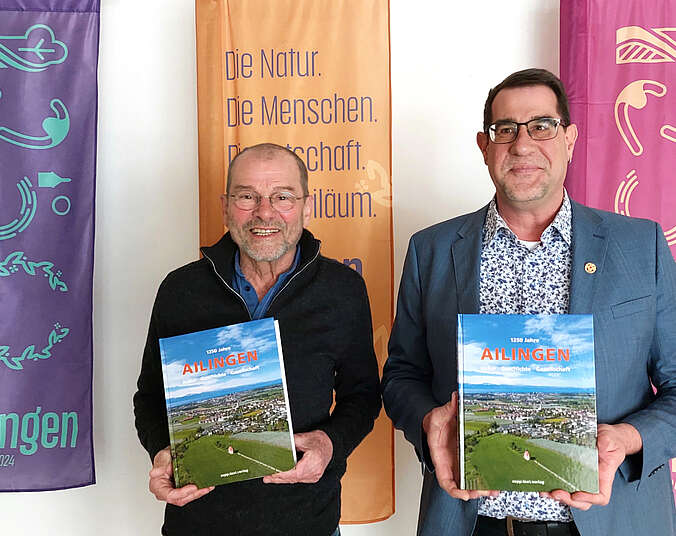 Redaktionsleiter Rainer Barth und Ortsvorsteher Andreas Lipp mit dem Jubiläumsbuch in den Händen