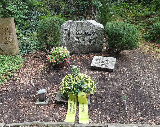 Grabstein davor eine Schale mit gelber Schleife