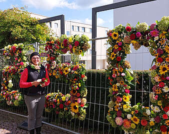 Frau steht vor einem großen Blumenarrangement