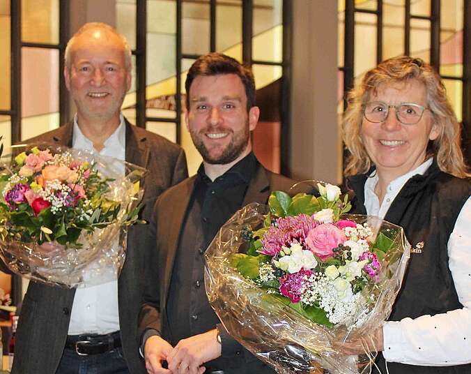 Zwei Männer und eine Frau mit Blumensträußen