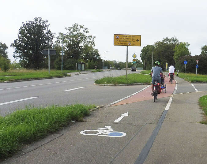 Fahrradmotiv mit blauem Hinterrad auf dem Boden weist Radlern den Weg.